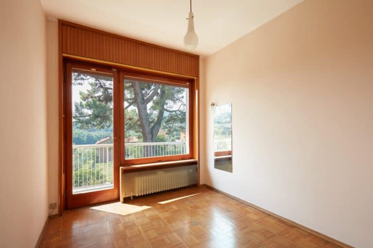 Empty room interior with parquet floor and terrace, sunlight